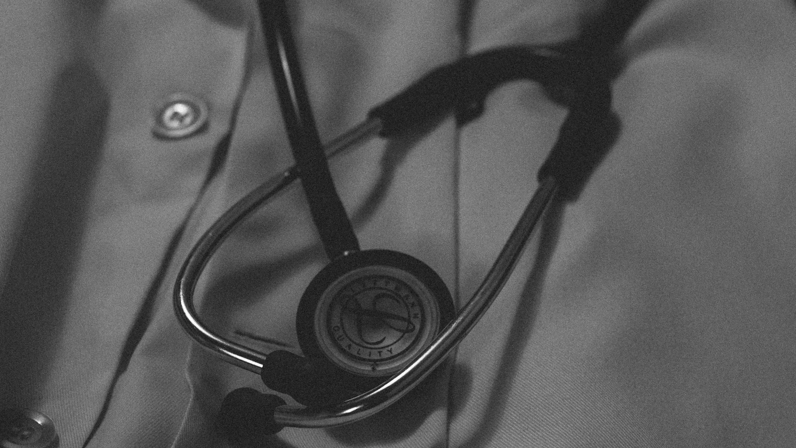 A doctor’s coat and stethoscope, in black and white